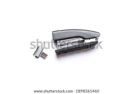 Black stapler with metal staples on white background.