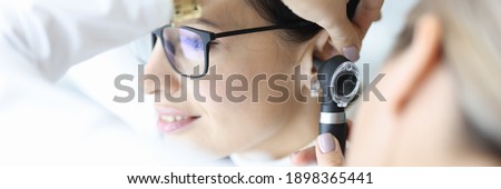 Otolaryngologist doctor examining patients ear with otoscope in clinic. Diagnosis of otitis media concept Royalty-Free Stock Photo #1898365441