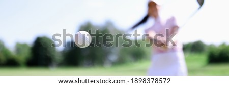 Golf ball against background of hitting woman closeup. Active healthy lifestyle concept