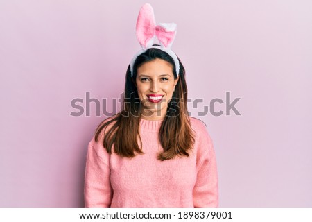 Beautiful hispanic woman wearing cute easter bunny ears with a happy and cool smile on face. lucky person. 