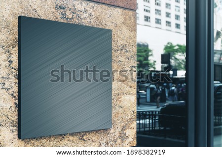 Black square sign with blank space for your logo on the marble wall of a modern business center, mockup