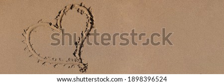 Heart drawn on the sand by sea closeup background. Romantic vacation for newlyweds at sea concept.
