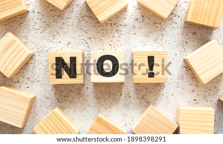 The word NO consists of wooden cubes with letters, top view on a light background. Work space.