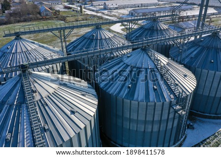 Snowy silos in winter. industrial elevator dryers, building exterior, storage and drying of cereals, wheat, corn, soybeans, sunflowers. Drone aerial view in Europe in Hungary