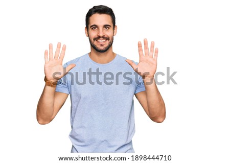 Young hispanic man wearing casual clothes showing and pointing up with fingers number ten while smiling confident and happy. 