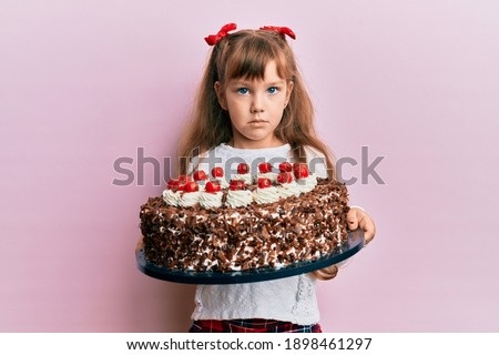 Little caucasian girl kid celebrating birthday holding big chocolate cake depressed and worry for distress, crying angry and afraid. sad expression. 