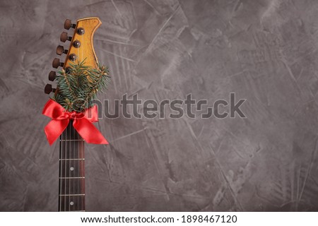 Guitar with fir tree branch and red bow on grey background, space for text. Christmas music