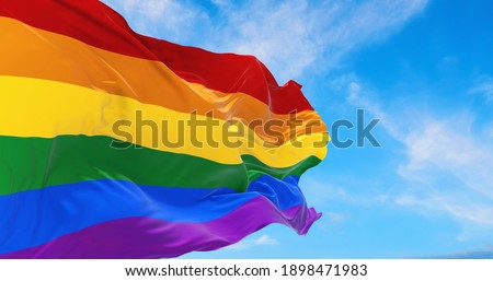 Pride rainbow lgbt gay flag being waved in the breeze against a sunset sky. Royalty-Free Stock Photo #1898471983