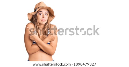 Young beautiful blonde woman wearing bikini and hat pointing to both sides with fingers, different direction disagree 