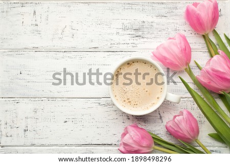 Good morning concept. Flat lay photo image of tasty cup of beverage and bunch of pastel pink color tulips on wooden rustic desk with blank empty space