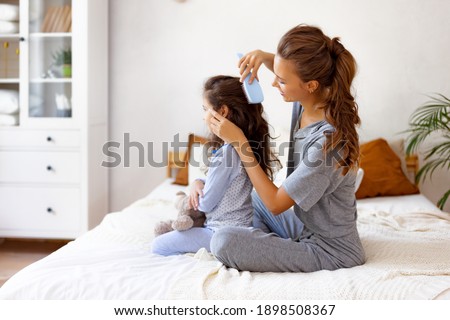 happy family mother combs her little daughter's hair while sitting in bed in the morning Royalty-Free Stock Photo #1898508367