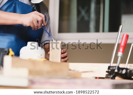 Woodworking operators are using glue to put together the wood parts to assemble and build a wooden table for their customers