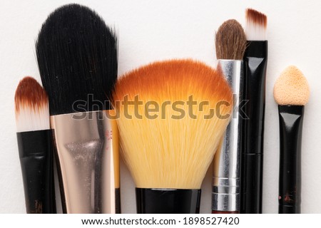 Top view cosmetics makeup for female on the white table background with Different brush types.