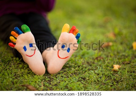 Close up of child human pair of feet painted with smiles outdoor in sunny park with bubble Royalty-Free Stock Photo #1898528335