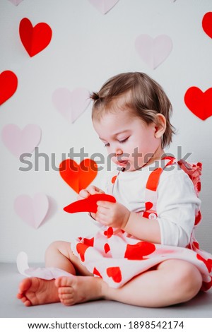 Little toddler girl in skirt with hearts on background with hearts celebrating Saint Valentine's day. Holiday decoration .
