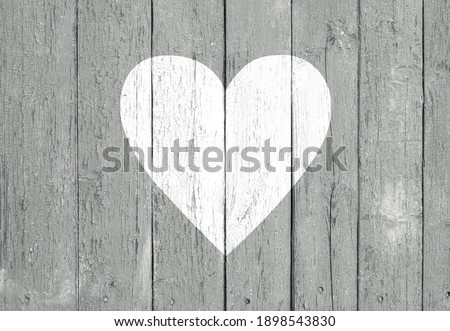 Old wooden board background with cracked gray paint and white heart shape. Valentine's day and love concept