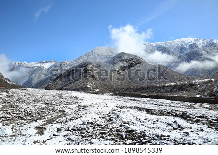 River bridge. Winter and mountains . There is fog at the foot of the mountains . It snowed on the river stones. In winter, the river water decreased
