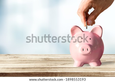 Businessman putting coin into the piggy bank Royalty-Free Stock Photo #1898553193