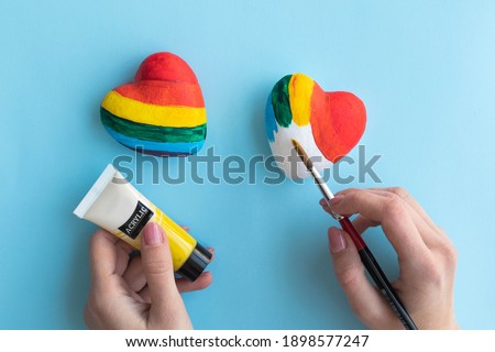 Girl paints heart in rainbow colors, concept of free lgbt love. High quality photo