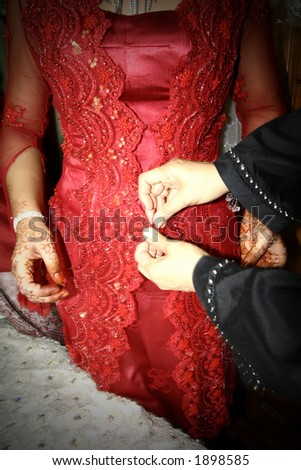 A red wedding dress being fastened at the waist.