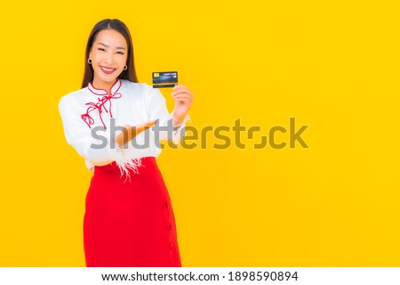 Portrait beautiful young asian woman with credit card for online shopping on yellow background