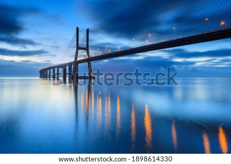 Background with nighy lights on the Lisbon bridge. The Vasco da Gama Bridge is a landmark, and one of the longest bridges in the world. Urban landscape. Portugal is an amazing tourist destinatio Royalty-Free Stock Photo #1898614330