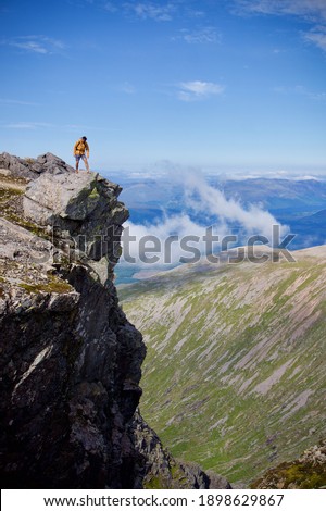View from Ben Nevis. Person on cliff edge on Ben Nevis, Scotland, UK. Sunny day hiker.  Royalty-Free Stock Photo #1898629867
