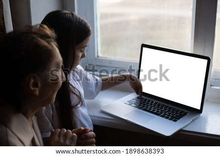 very elderly great-grandmother and granddaughter with laptop online