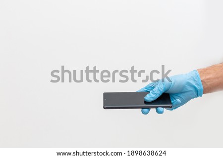 hand in blue glove is holding touchscreen smartphone in his hands. Isolated on white background