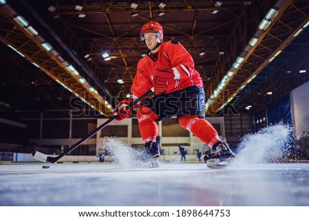 Low angle view of hockey player skating and playing ruffly.