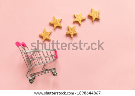 Simply flat lay design small supermarket grocery push cart for shopping and 5 gold stars rating isolated on pink pastel background. Retail consumer buying online assessment and review concept Royalty-Free Stock Photo #1898644867