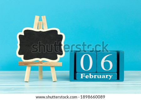 wooden calendar with the date of February 6 and an easel on a blue background, place for text, International Day for the intolerance of female genital mutilation	
