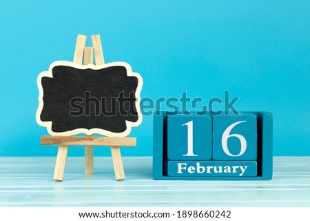 wooden calendar with the date of February 16 and an easel on a blue background, place for text, International Day of Canadian Heritage	
