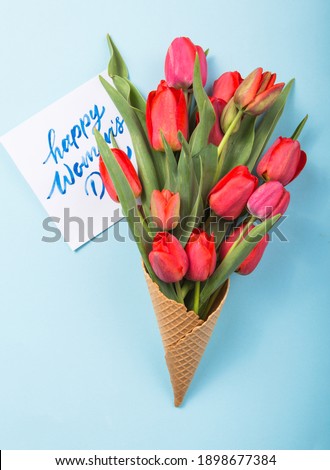 red tulip bouquet on pastel colored background, copy space, text place.  International Woman day on paper 