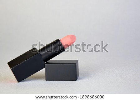 Beauty and makeup. Single black tube of natural color lipstick on gray background. Close-up. Copy space. Royalty-Free Stock Photo #1898686000