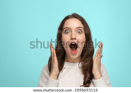 Close up portrait of beautiful darkhaired woman spreading hands, standing isolated over background, astonished female with widely opened mouth wearing ssweater. People wow emotions concept. Royalty-Free Stock Photo #1898693116