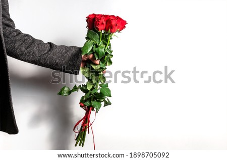 Man's hand with a bouquet of red roses on a white background. Copy space