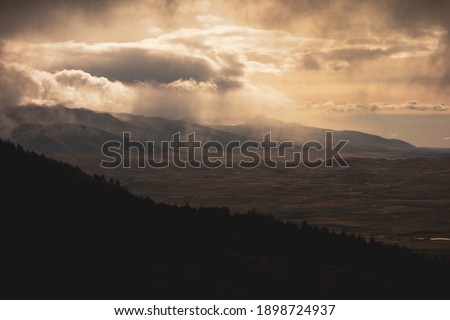 Dramatic weather as rainclouds pass by sun over Torres del Paine landscape Royalty-Free Stock Photo #1898724937