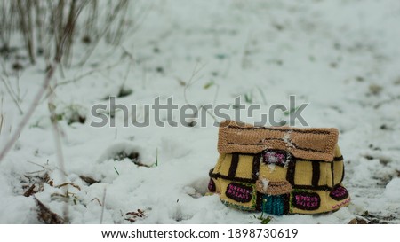 photo of a small knitted toy house in the snow