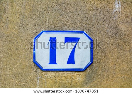 house number seventeen ( 17 ) on a roughcast wall