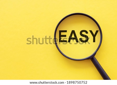The word EASY is written on a magnifying glass on a yellow background.
