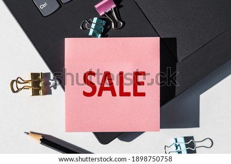 SALE note is written on a paper sticker on a laptop keyboard.