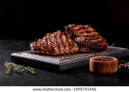Fresh juicy delicious beef steak on a dark background. Meat dish with spices and herbs Royalty-Free Stock Photo #1898765446