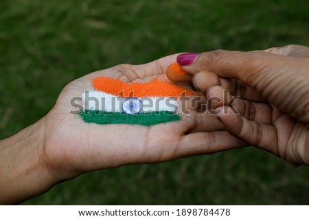Female putting rangoli on palm on occasion of Indian republic day and Independence at home lockdown.Indian flag tattoe design depicting freedom, unity, happiness, peace and written constitution
