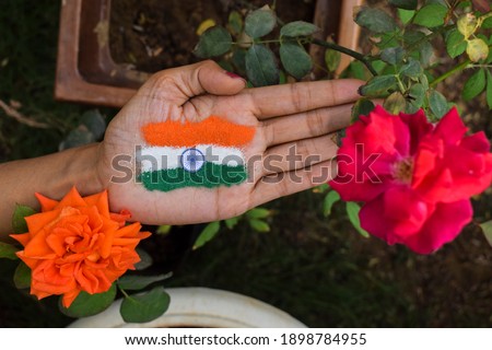 Female putting rangoli on palm on occasion of Indian republic day celebration at home lockdown. Tri color Indian flag tattoe design depicting freedom, unity. decoration of flowers