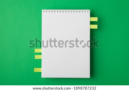 Above overhead close up mock up view photo of clear spiral notebook with memo notepapers isolated bright color green table backdrop