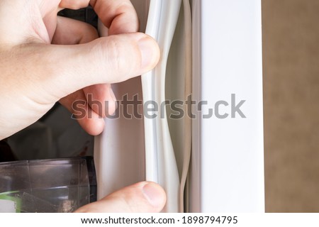 broken refrigerator door seal. appliance repair service concept. replace fridge door sealant or gasket. Royalty-Free Stock Photo #1898794795