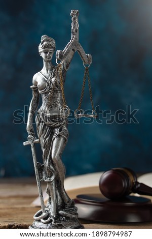 Themis statue justice scales and judge's gavel with Constitution background on dark blue surface. Symbol of law. Law concept.