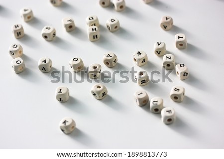 Alphabet black and white cube beads scattered on the white table background flat lay, contrast shadows
