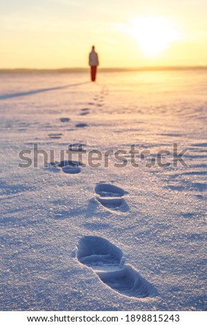 Footprints in the snow. The girl leaves towards the sunset